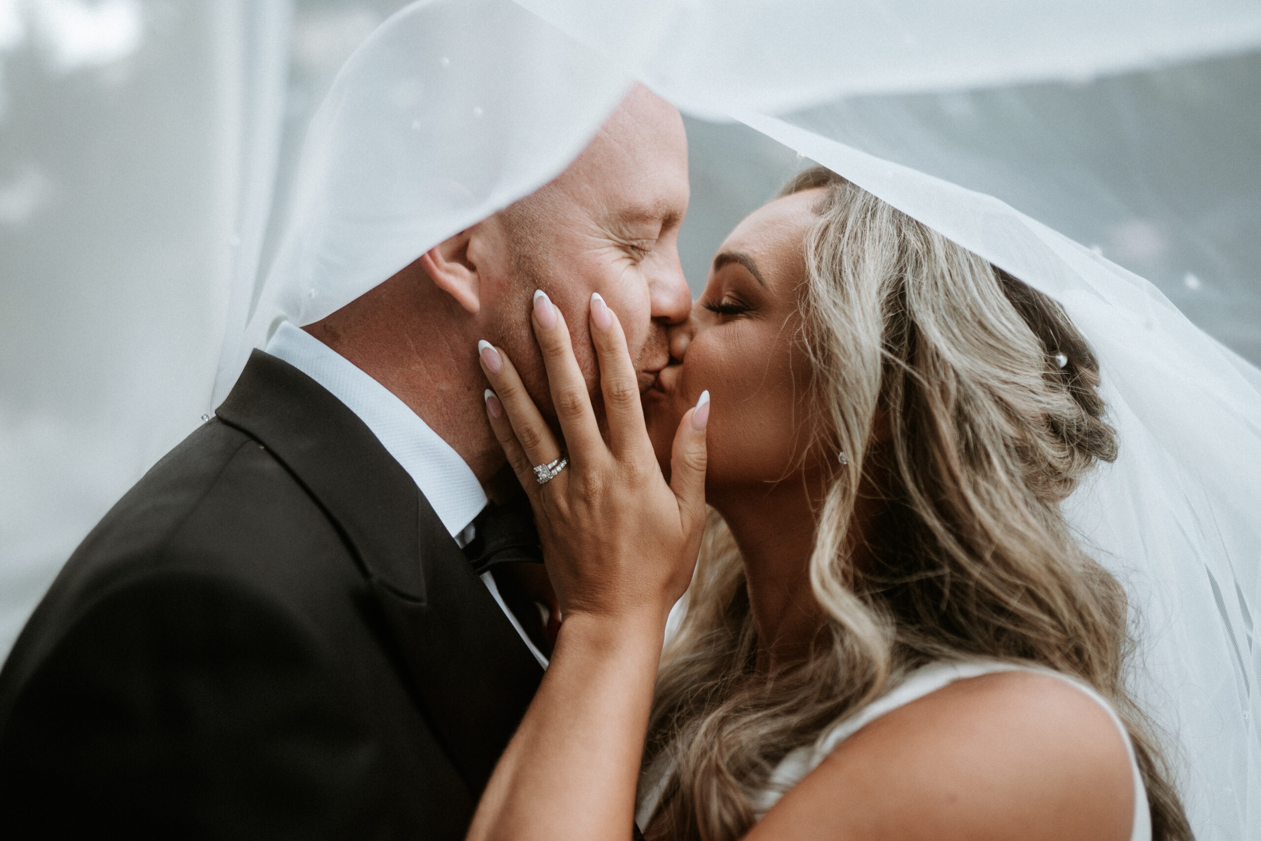 Stealing an intimate moment under the veil to seal their commitment to each other with a kiss.